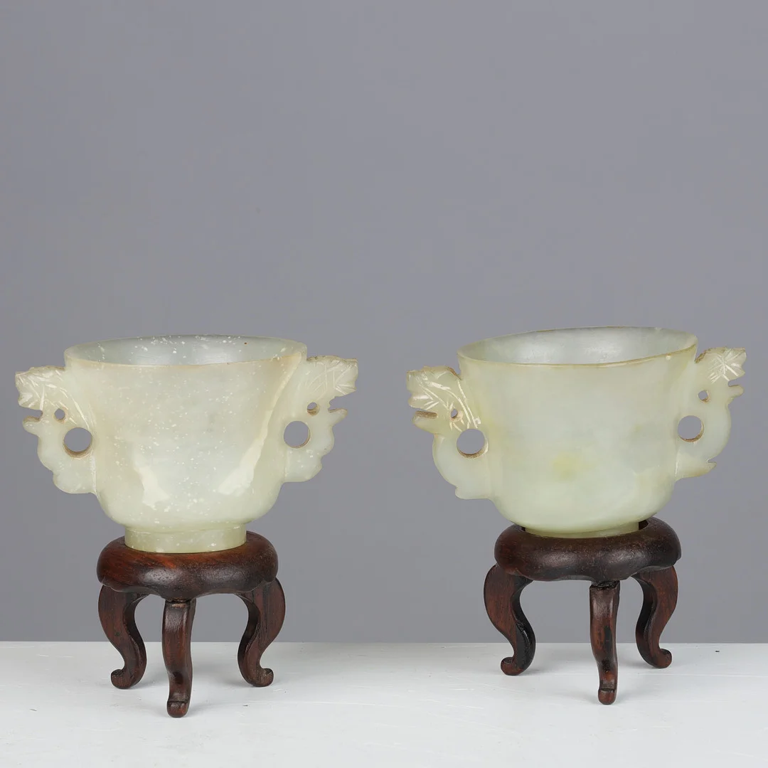 To små bægre af lys celadon jade med stande af træ, 19-20 årh. (2+2). — Jade — Palsgaard Kunstauktioner