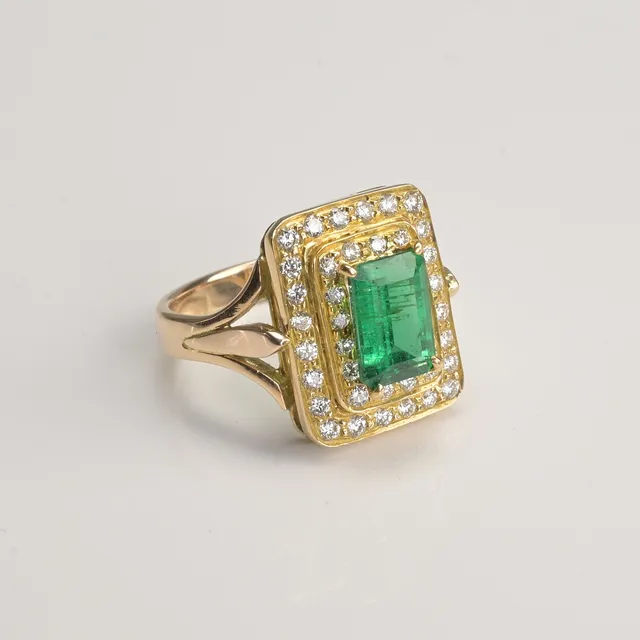 18CT ROSE / YELLOW GOLD, EMERALD AND DIAMOND HALO RING.