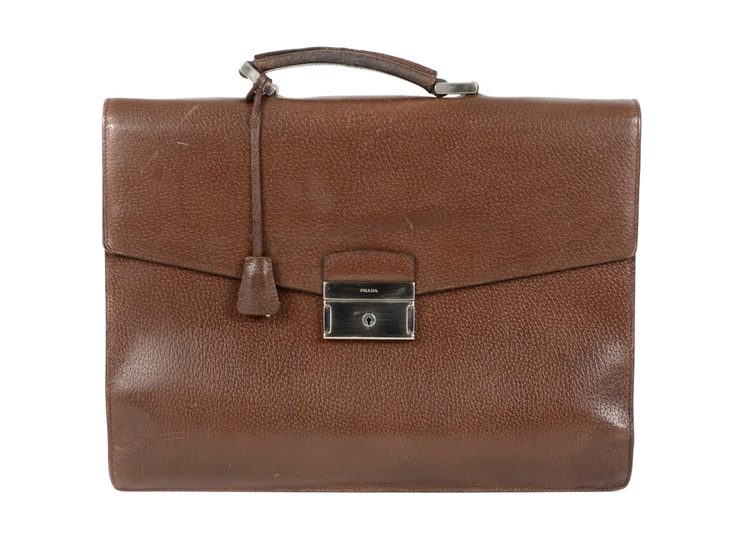 PORTFÖLJ, PRADA, brunt läder, spänne i vitmetall, 37x27x11cm, dustbag, bläckfläck inne i väskans botten, visst slitage, — Accessoarer/Väskor — Kaplans