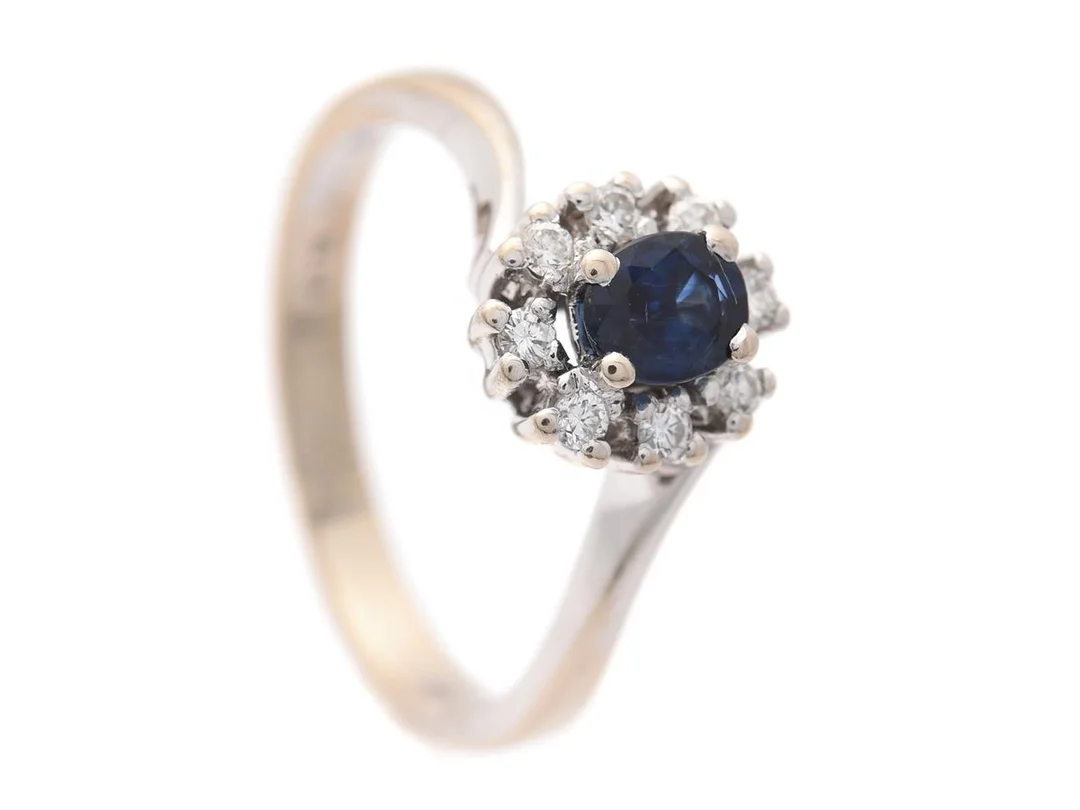 CARMOSÈRING, 18K rodinerat guld, ovalslipad blå safir 0,49 ct, 8 briljantslipade diamanter ca 0,16 ctv, ca W/SI, stl 17,5 mm, vikt 4,0 g, safiren har nagg. — Smycken/Carmoséring — Kaplans