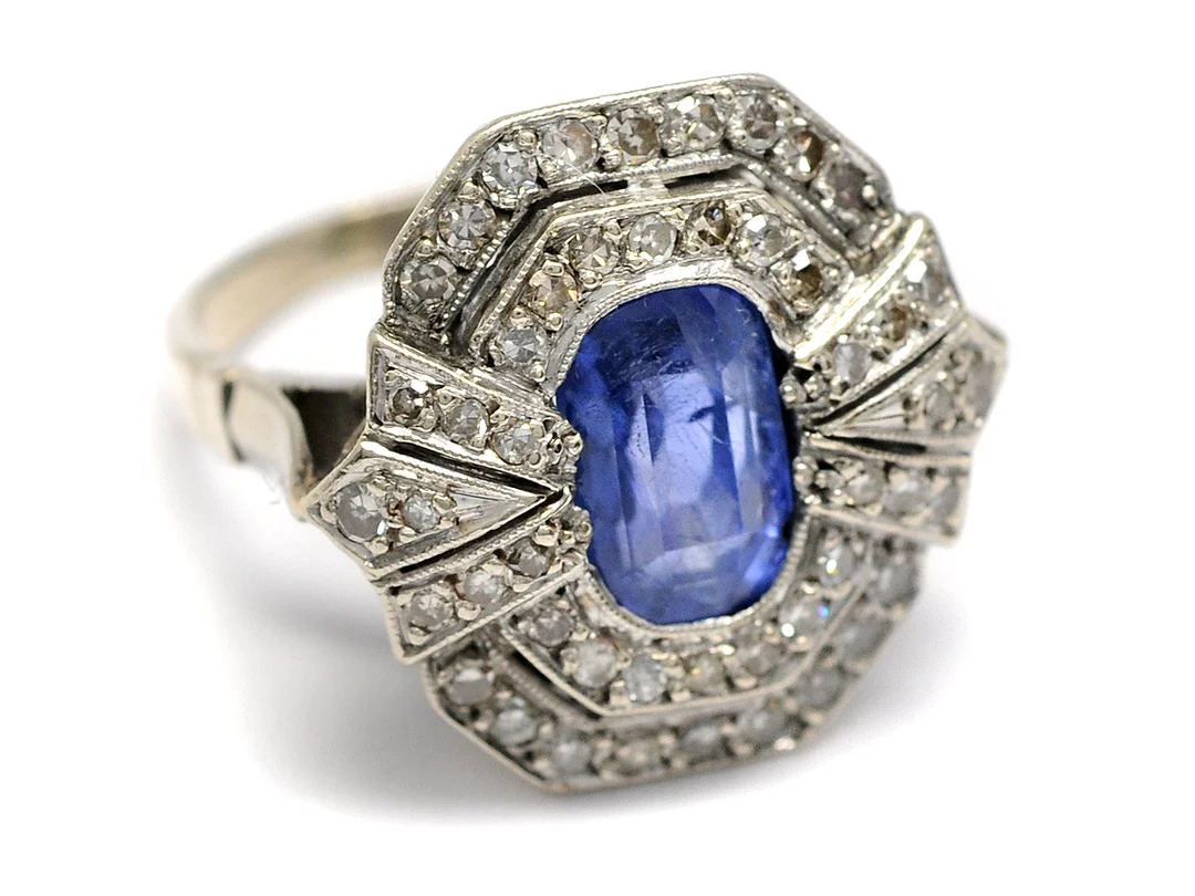 RING, 14K vitguld, ovalslipad safir, inneslutningar som når ytan, 48 åttkantslipade diamanter ca 0,48 ctv, 3 skadade, stl 16 mm, vikt 4,9 g, svaga fattningar. — Smycken/Ring — Kaplans