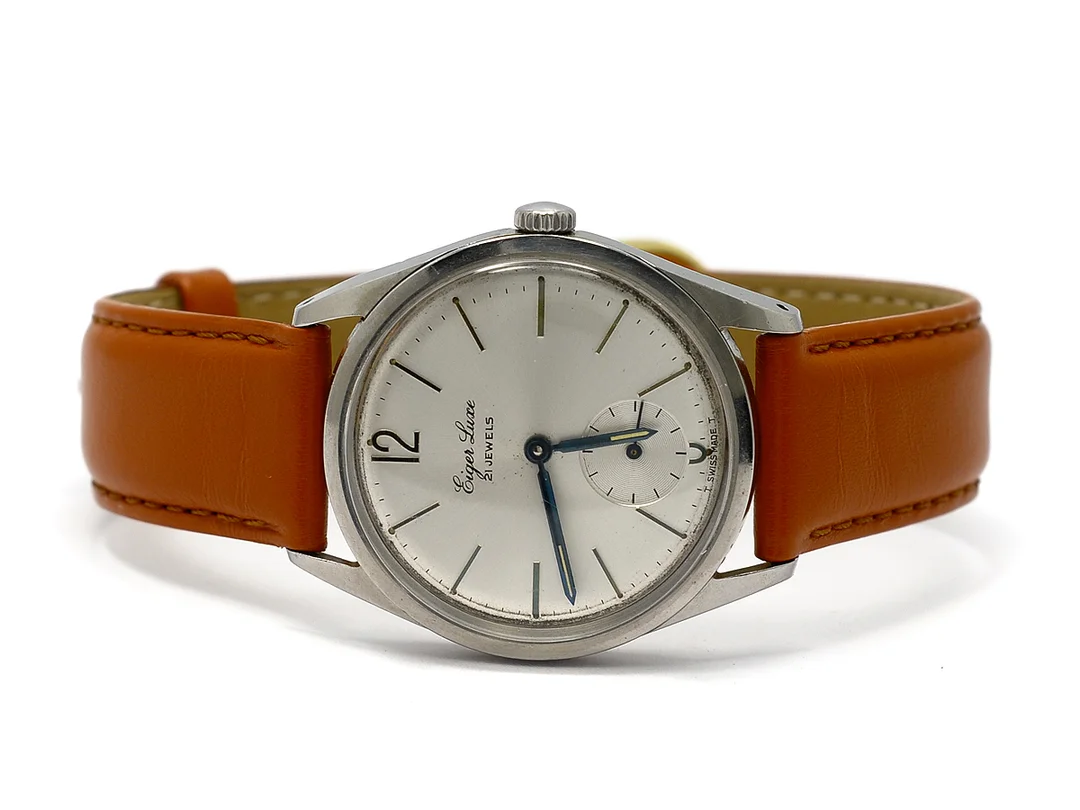 EIGER LUXE, herrur, 34 mm, Boett nr. 103250, vitmetall, manuell, plexiglas, liten sekundvisare, skadad urtavla, defekt, skadad boett, läderband, ca 1958. — Klockor/Övriga klockor — Kaplans