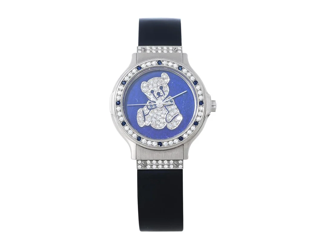 HUBLOT, Geneve, MDM, "Teddy Bear", Serie nr. 282974, Boett nr. 1392.4.061, damur, 28 mm, 18K vitguld, quartz, safirglas (repor), urtavla i emalj, urtavla med diamanter (50 st.) och safirer (6 st.), diamanter (64 st. ca TW/VVS, ca 0,36 ctv) och safirer (12 st.) på boetten, integrerat gummiband, viklås i 18K vitguld, längd 170 mm, ca 1995, serviceetui. Limiterad och numrerad (Nr. 07/30). — Klockor/Hublot — Kaplans