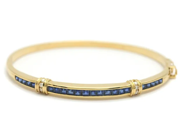 ARMRING, 18K guld, 22 carréslipad blå safirer, 8 briljant ca 0,08 ctv, mått 5,6 x 5,1 cm, vikt 14,1 g.
