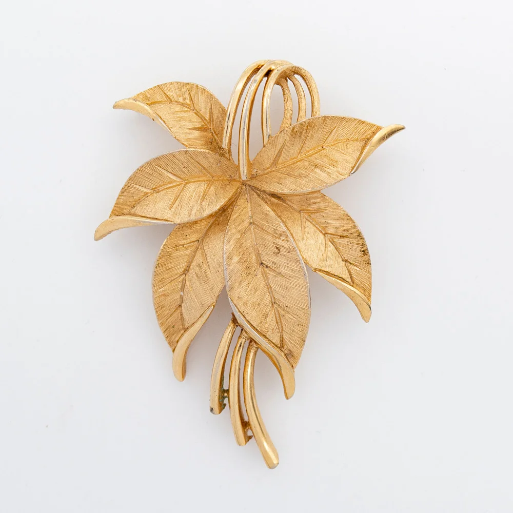 BROSCHE DER FIRMA CROWN TRIFARI, FORM EINES SANFT GESCHWUNGENEN BLATTES AUS VERGOLDETEM, FEIN GEBÜRSTETEN TRIFANIUM, SIGNIERT MIT CROWN TRIFARI, 1960ER JAHRE. — Brooches & Pendants — Kunst- und Auktionshaus Kleinhenz