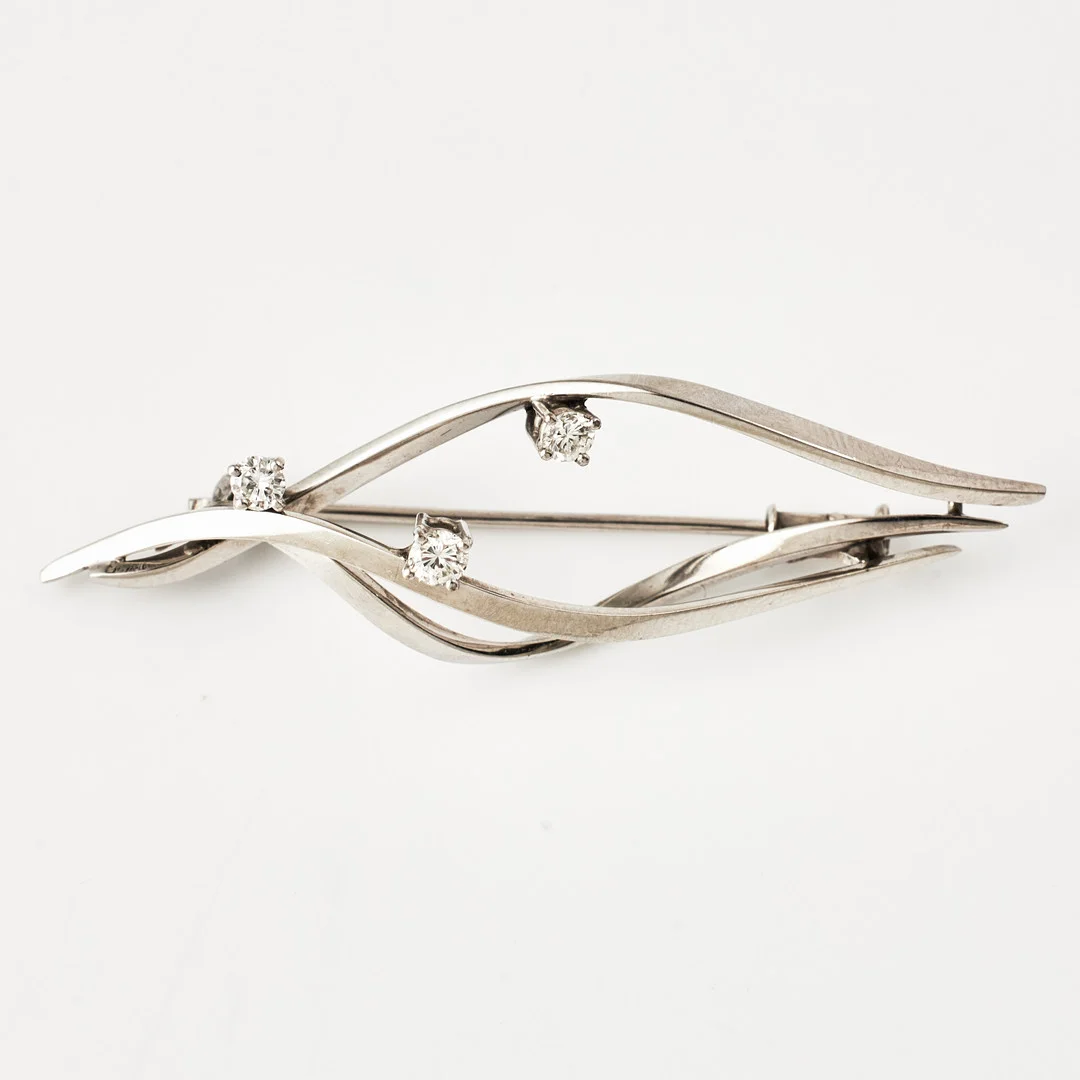 BROSCH, 18 k vitguld, 3 briljanter, ca 0,25 ct, enligt uppgift Peter Rateitschak. — Brooches & Pendants — Stockholms Auktionsverk Magasin 5