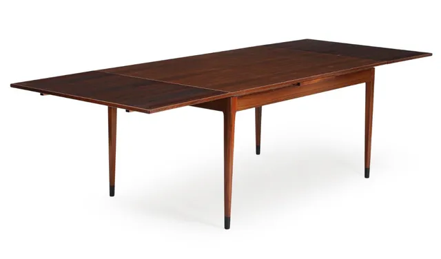 A rosewood dining table with extension, dark lacquered shoes. Manufactured and marked by J. L. Møller's Møbelfabrik. 1960s. H. 73. L. 150/264. W. 100 cm.