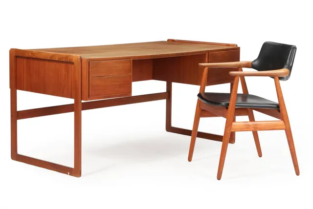 A teak armchair, upholstered in seat and back with black artificial leather. Manufactured by Glostrup Møbelfabrik. And a freestanding teak desk on runner legs, front with four drawers and back with three shelves. H. 70.5. L. 150. W. 75 cm. (2)