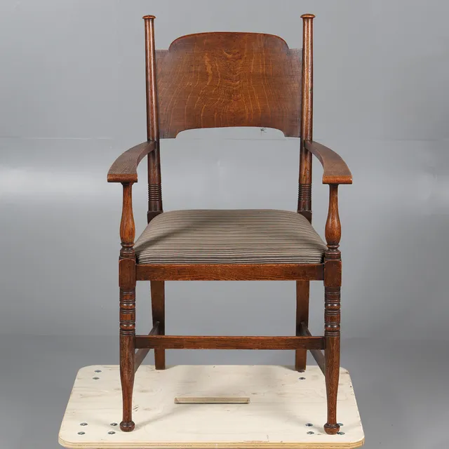 AN ARTS AND CRAFTS OAK OPEN ELBOW CHAIR PROBABLY BY WILLIAM BIRCH FOR LIBERTY & CO.