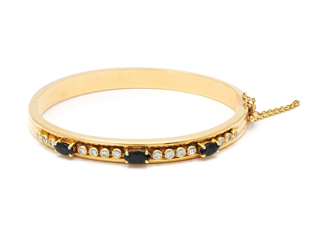 ARMRING, 18K guld, 3 blå safirer, navettslipade, 14 briljantslipade diamanter ca 0,56 ctv, ca W/SI, 1 diamant skadad, längd 18 cm, vikt 16,7 g, öppningsbar. — Smycken/Armring — Kaplans