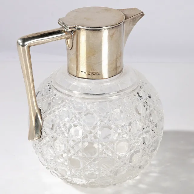EDWARDIAN SILVER AND GLASS CLARET JUG.