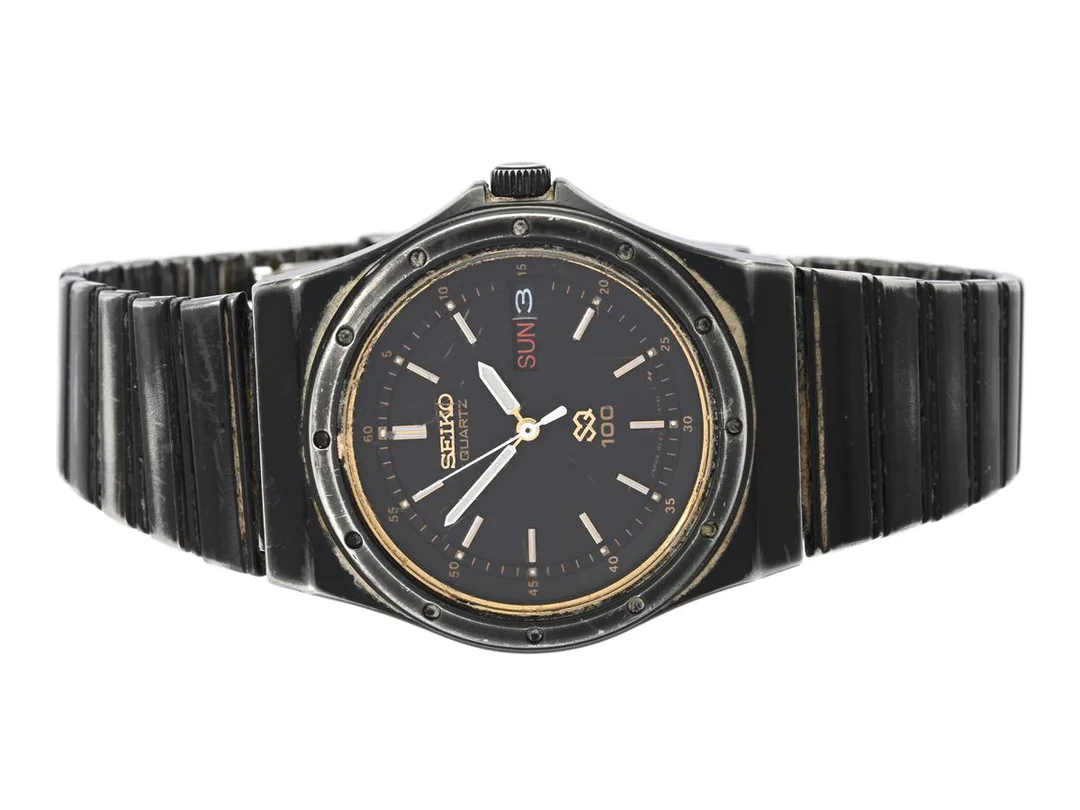 SEIKO, SQ 100, Serie nr. 642403, Boett nr. 8C23-6070, herrur, 34 mm, svart stål, quartz (går ej), hardlexglas, dag, datum, originallänk, viklås, ca 1986. — Klockor/Seiko — Kaplans
