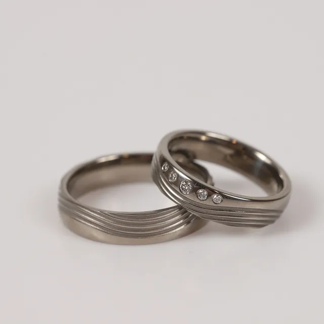 ALLIANSRINGAR, 2 stycken, titan med bl. a. briljantslipade diamanter, totalt 0,087 ct.