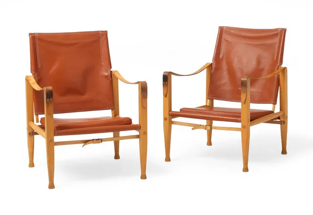 A pair of safari chairs with ash frame. Seat and back of brown leather. Full grain leather armrests and straps.Made by Rud. Rasmussen cabinetmakers. (2)