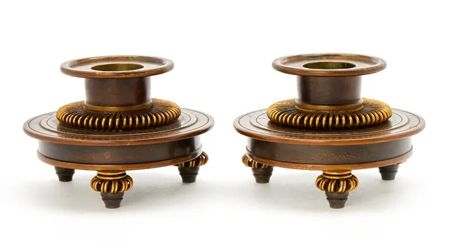 A pair of patinated and partially gilded bronze candlesticks, mounted on three feet. Stamped monogram KA for Knud Andersen. H. 7 cm. Diam. max. 10.5 cm. Candle socket interior diam. 3. (2)