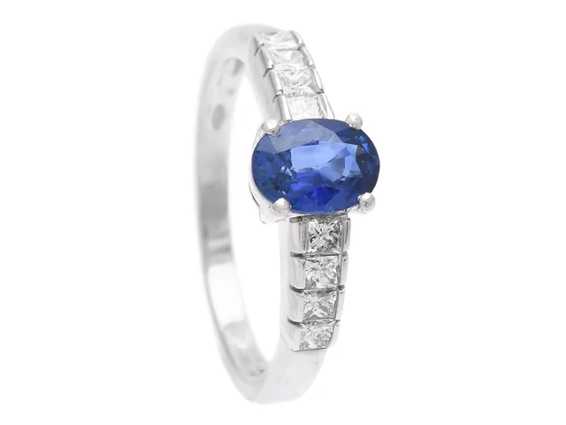 RING, 18K vitguld, ovalslipad blå safir ca 1,10 ct, 8 prinsesslipad diamant ca 0,54 ctv, ca W/VS, stl 17 mm, vikt 3,7 g, safir med nindre nagg, en diamant skadad.