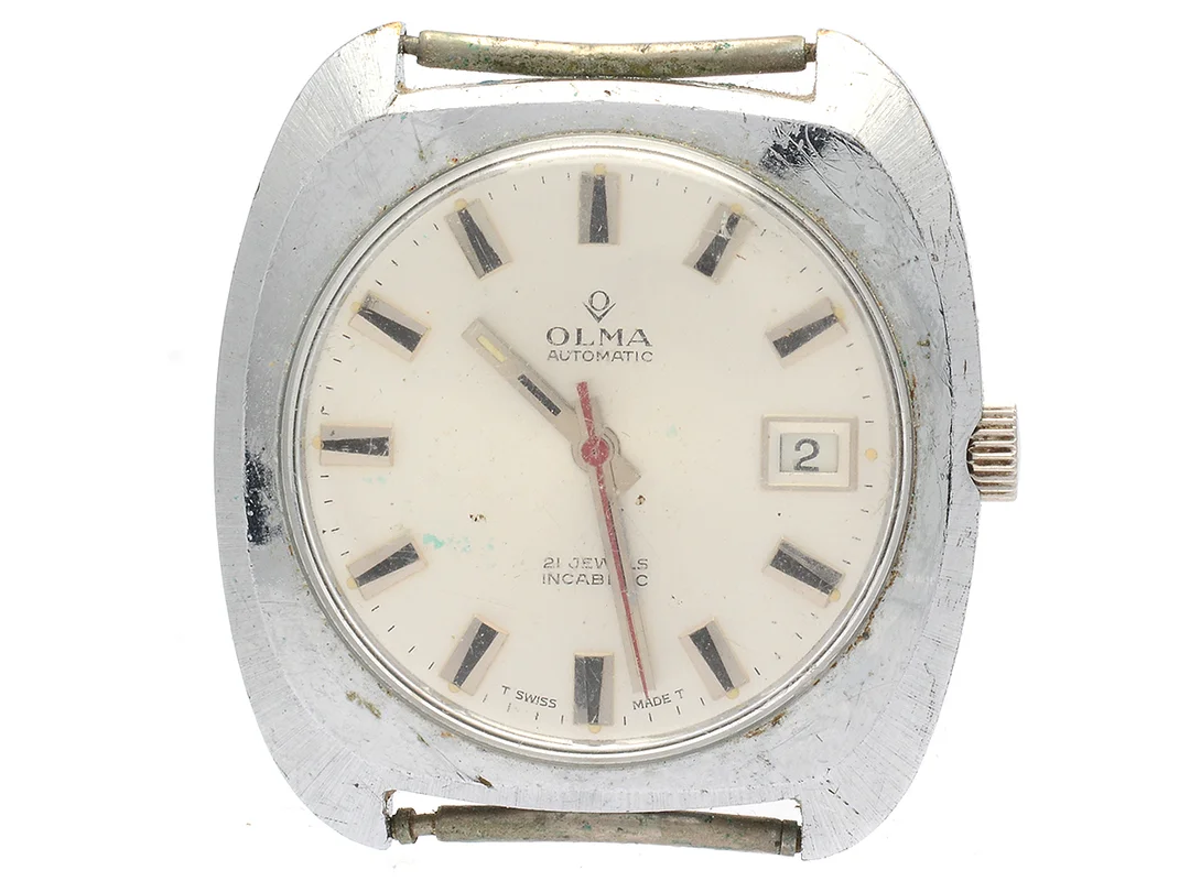 OLMA, herrur, 37,5 mm, Boett nr. 0799-3, vitmetall, automatisk, plexiglas, datum, skadad urtavla, ca 1970. — Klockor/Olma — Kaplans
