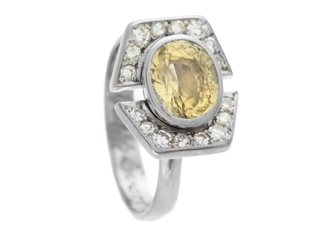 RING, 18K vitguld, ovalslipad gul safir, 16 åttkantslipade diamanter 0,31 ctv enligt gravyr, ca TW-Cr/VS, stl 17,5 mm, vikt 6,5 g, safir med slitna fasettkanter, en diamant skadad, en diamant med brännmärken. — Smycken/Ring — Kaplans