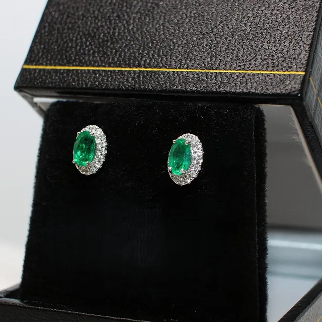 18K WHITE GOLD EMERALD AND DIAMOND STUDS.