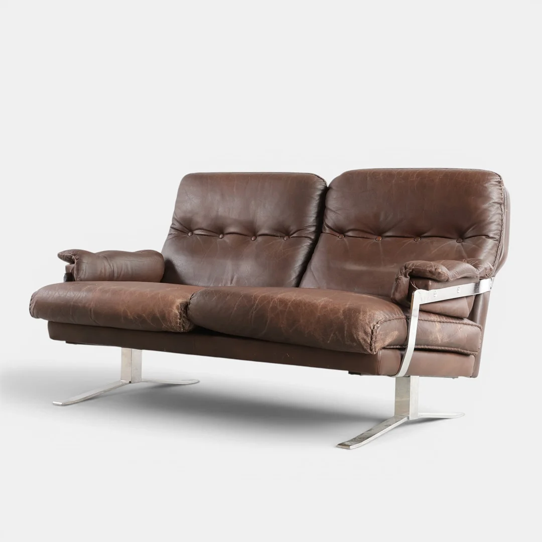 ARNE NORELL. Fritstående to-pers. sofa med shakerstel af forkromet metal, betrukket med brunt bøffellæder, løse hynder i sæde. Udført hos Vatne Møbler. Norge, 1960-70'erne. — Sofas & Seatings — Woxholt Auktioner