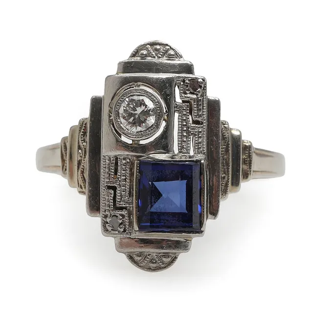 A sapphire and diamond ring set with a faceted sapphire, a brilliant-cut diamond and two rose-cut diamonds, mounted in 14k white gold. Weight app. 2.5 g. Size 54.