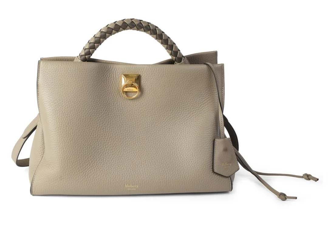 An “Iris” bag of grey leather with gold tone hardware, woven handle, adjustable and detachable shoulder strap, one compartment with magnetic closure, two interior pockets of which one has a zip fastener, and grey suede lining. H. 24 x W. 35 x D. 18 cm. — Designer Handbags & Fashion/Designer Handbags — Bruun Rasmussen