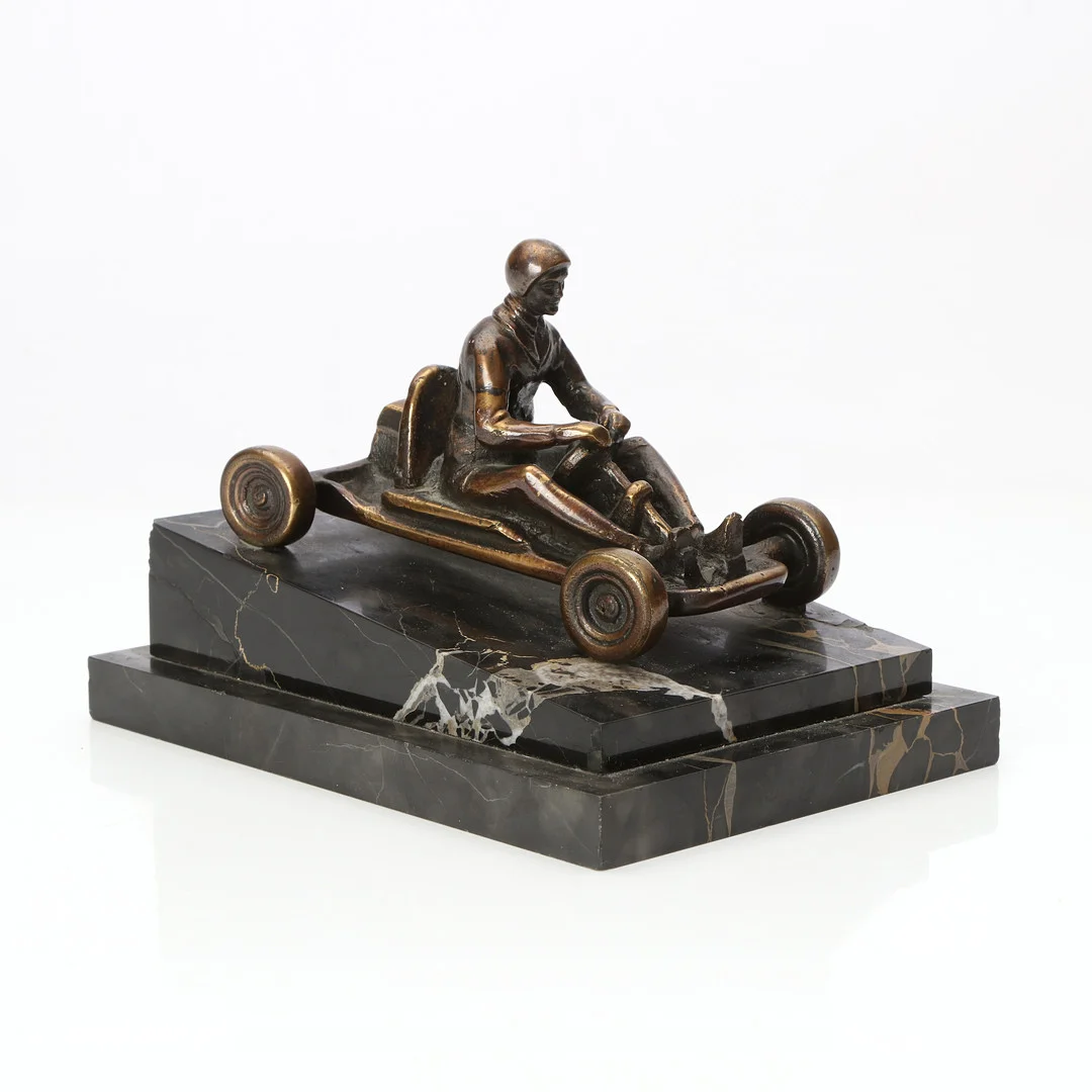 OKÄND KONSTNÄR. SKULPTUR. Patinerad brons på marmorsockel. Gocartförare. 1900-talets andra hälft. — Sculptures & Bronzes — Skånes Auktionsverk