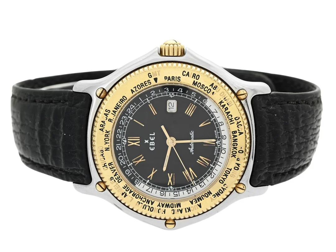 EBEL, Voyager, Cal 124 (ETA 2892A2), Serie nr. 34601872, Ref nr. 1124913, herrur, 39 mm, stål/guld, automatisk, safirglas, världstidsvisning, skadad urtavla, integrerat läderband, viklås, cert, maj 1990. — Klockor/Ebel — Kaplans