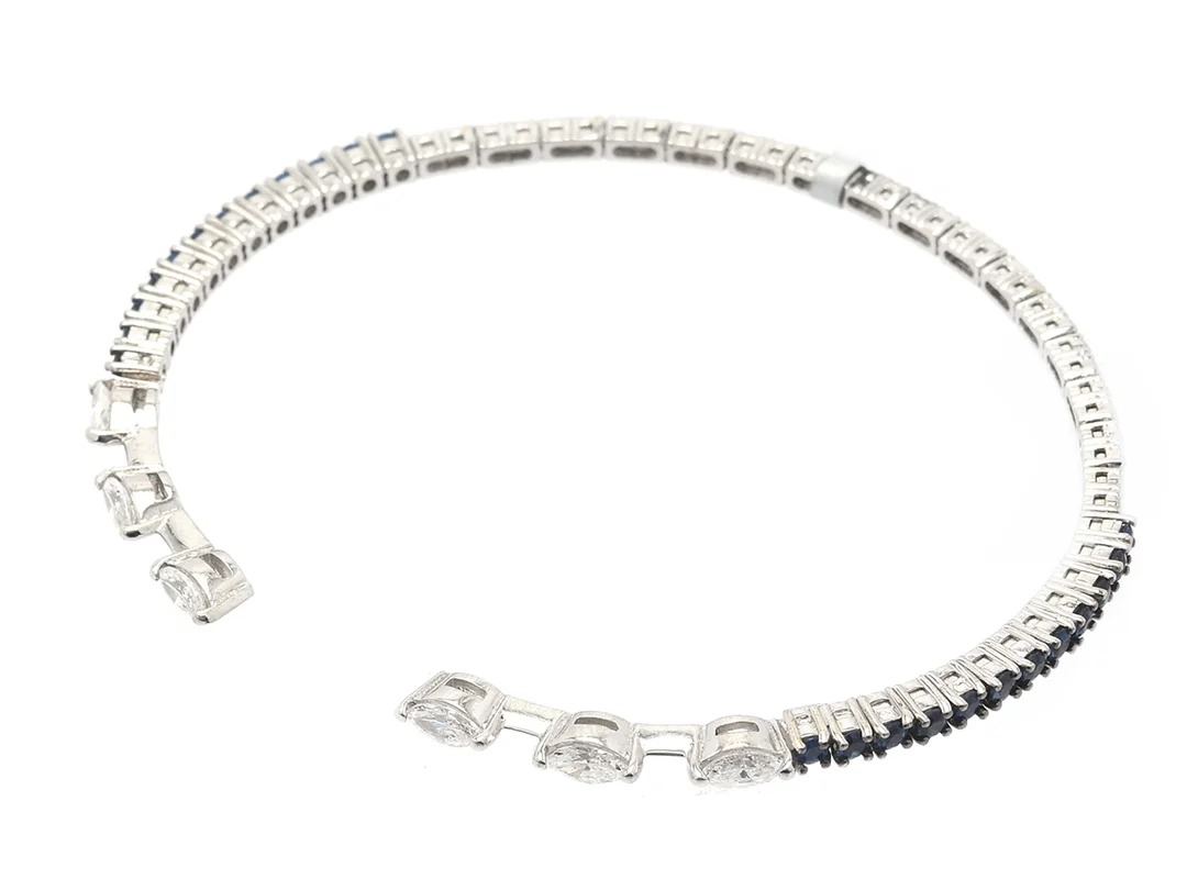 ARMRING, 18K vitguld, 6 navettslipade diamanter ca 0,60 ctv ca TW-W/VS-SI, safirer ca 0,78 ctv, flexibelt, mått 54 x 45 mm, vikt 7,9 g. — Smycken/Armring — Kaplans