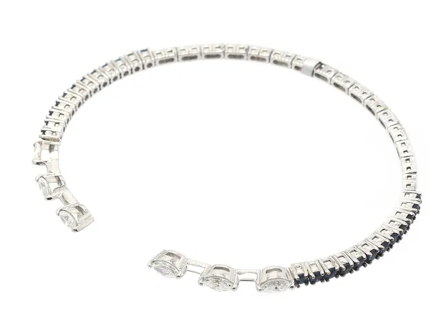 ARMRING, 18K vitguld, 6 navettslipade diamanter ca 0,60 ctv ca TW-W/VS-SI, safirer ca 0,78 ctv, flexibelt, mått 54 x 45 mm, vikt 7,9 g.