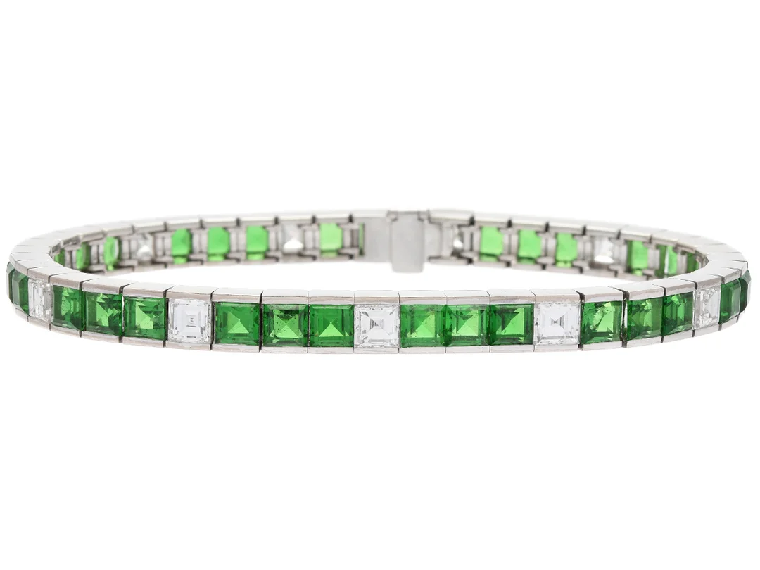 ARMBAND, 18K vitguld, 33 tsavoriter ca 14,00 ctv, 11 carréslipade diamanter ca 4,40 ctv, ca TW(F-G)/VVS-VS, längd 18 cm, vikt 29,6 g, en tsavorit skadad samt en tsavorit med nagg. — Smycken/Armband — Kaplans