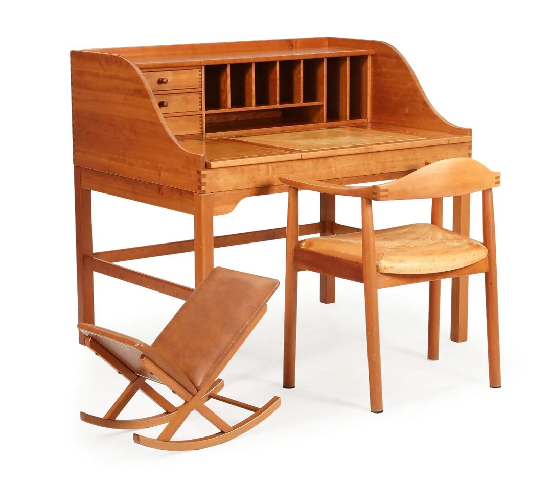 A freestanding solid cherry wood writing desk, front with storage room and three drawers, table top with two small flaps and one larger, middle flap covered with natural leather. And an armchair upholstred in seat with natural leather. And a rocking footstool with brown leather. Manufactured respectively by Hadsten Møbelindustri and Form75. H. 103. L. 111. W. 82 cm. (3) — Modern Furniture — Bruun Rasmussen