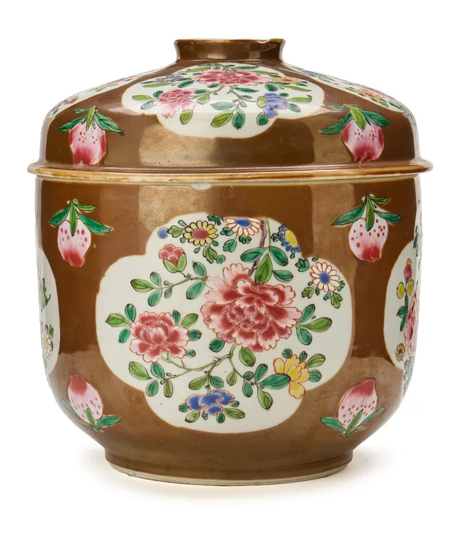 A Chinese lidded jar, Batavian ware, decorated in Capuchin-brown glaze with famille rose flowers in cartouches. Qing dynasty 18th century. H. 24 cm.
