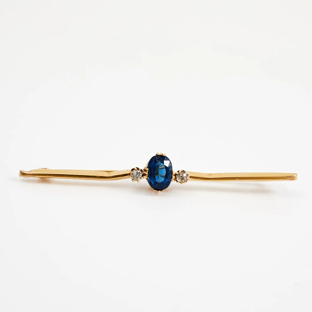 BROSCHNÅL, 18 k guld, fasettslipat blått glas, flankerad av 2 syntetiska vita safirer, Harbeck Wilhelm, Stockholm, 1921. — Brooches & Pendants — Stockholms Auktionsverk Sickla