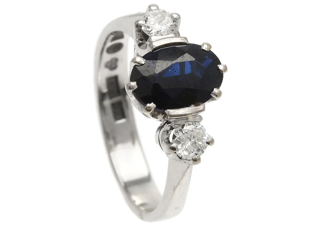 RING, 18K vitguld, fasetterad blå safir ca 1,3 ct, 2 briljatslipade diamanter ca 0,24 ctv, ca W(H)/VS, stl 16,5 mm, Stockholm 1975, vikt 4,5 g, en diamant skadad, safiren har nagg och slitna fasettkanter. — Smycken/Ring — Kaplans
