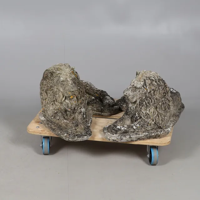 A PAIR OF RECONSTITUTED STONE RECUMBENT LIONS.