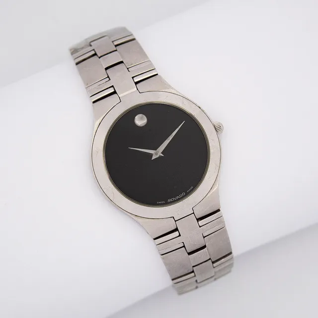 MOCADO JURO ARMBANDUHR, QUARTZWERK, EDELSTAHL MIT EINEM CHARAKTERISTISCHEN SCHWARZEN ZIFFERBLATT, KRATZFESTES SAPHIRGLAS, BIS ZU 30 METER WASSERDICHT, SILBERFARBENER STUNDENINDEX BEI 12 UHR, EDELSTAHLARMBAND.