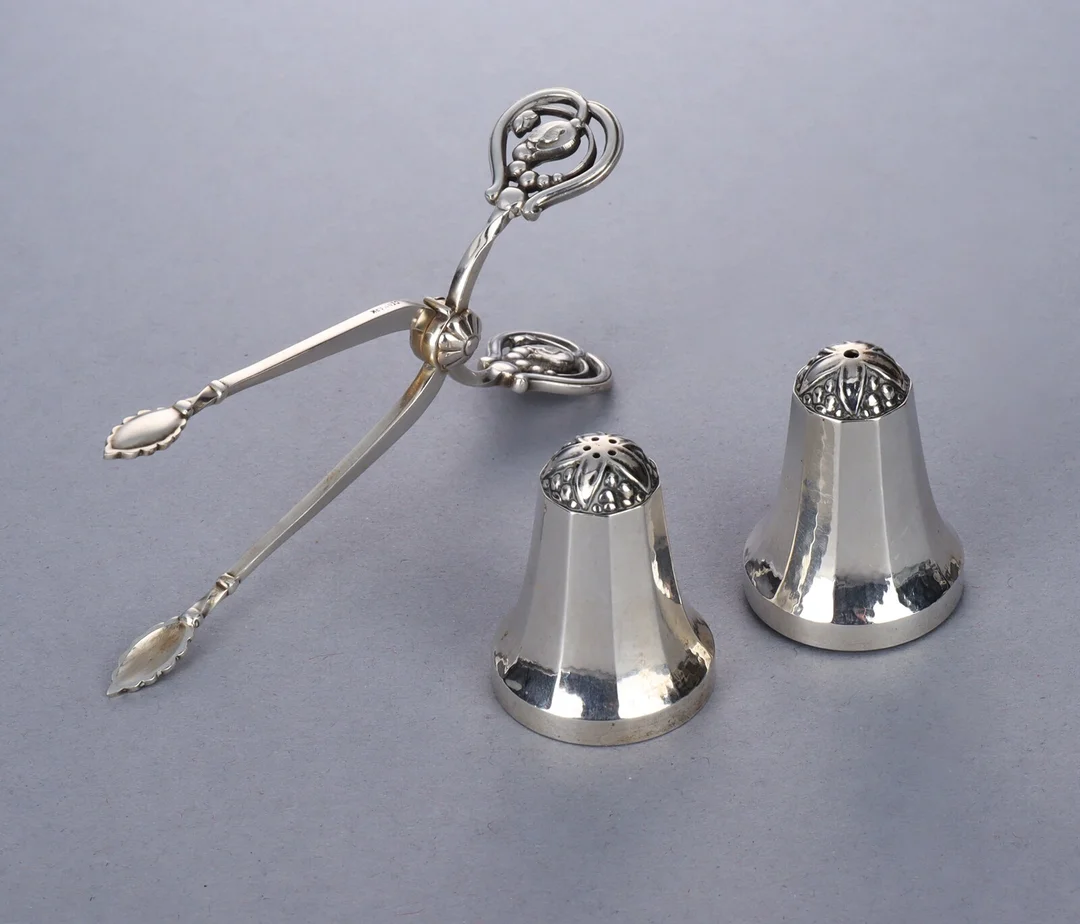 Georg Jensen. 'King' salt and pepper set and 'Magnolia' sterling silver tongs (3) — Silver, bronze, copper and pewter/Hollowware — Lauritz
