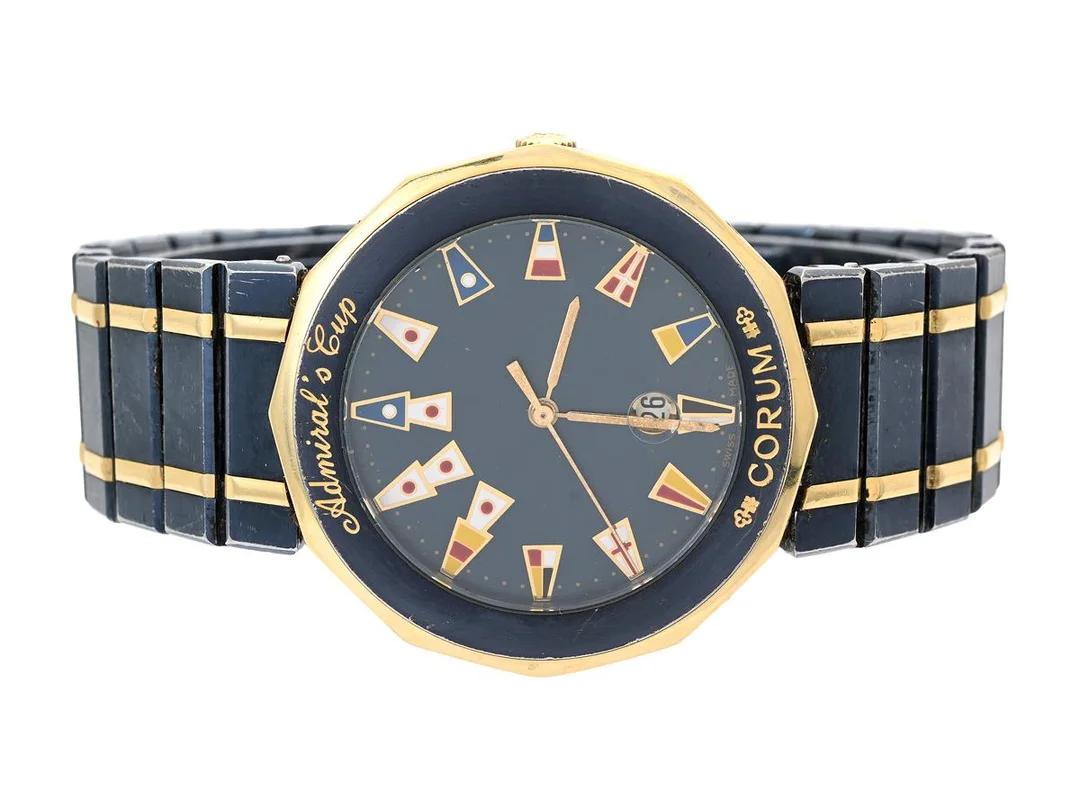 CORUM, Admiral´s Cup, Ref nr. 99.810.31 V-52B, Boett nr. 436850, herrur, 35 mm, blåeloxerad stål/guld, quartz, safirglas, datum, skadade visare, urverk ej signerad, integrerad originallänk, viklås, ca 1995. — Klockor/Corum — Kaplans