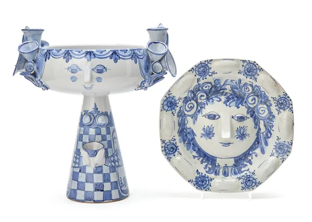 Earthenware wall relief and tazza modelled in the shape of resp. a womans' face and a womans' figure. Decorated with resp. blue and blue/rose glazed decor on a light grey glazed base. Signed monogram, Danmark resp. -68, D12 and -82, V.14. Wall relief: D. 7 cm. Diam. 26.5 cm. Tazza: H. max. 34 cm. W. 32 cm. The inner diam. of candle holders: 2.4 cm. (2)