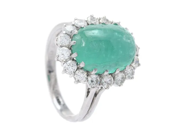 CARMOSÉRING, 18K vitguld, cabochonslipad smaragd ca 6,00 ct, 16 briljantslipade diamanter ca 0,98 ctv, ca TW-TCr(G-I)/VS-SI, stl 17,75 mm, vikt 6,8 g, smaragden har interna sprickbildningar varav vissa öppnar sig vid ytan, några av diamanterna har mindre nagg.