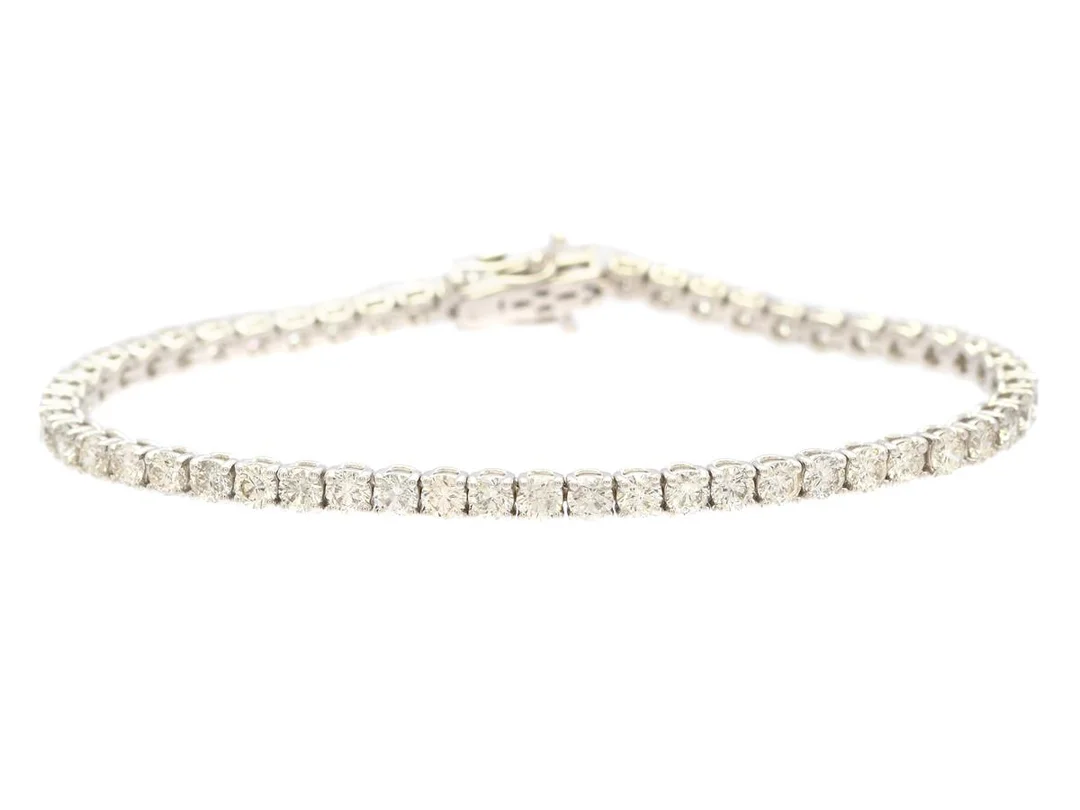 TENNISARMBAND, 18K vitguld, 53 briljantslipade diamanter ca 5,30 ct ca TW-TCr/VS-SI, längd 16,7 cm, enstaka diamanter med nagg och skador. — Smycken/Tennisarmband — Kaplans