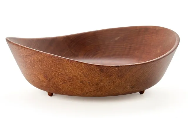 A solid teak bowl with three small feet. Made and marked by Kay Bojesen, Denmark. Copyright, Finn Juhl Design. H. 7.5 cm. W. 22 cm. L. 23.6 cm.