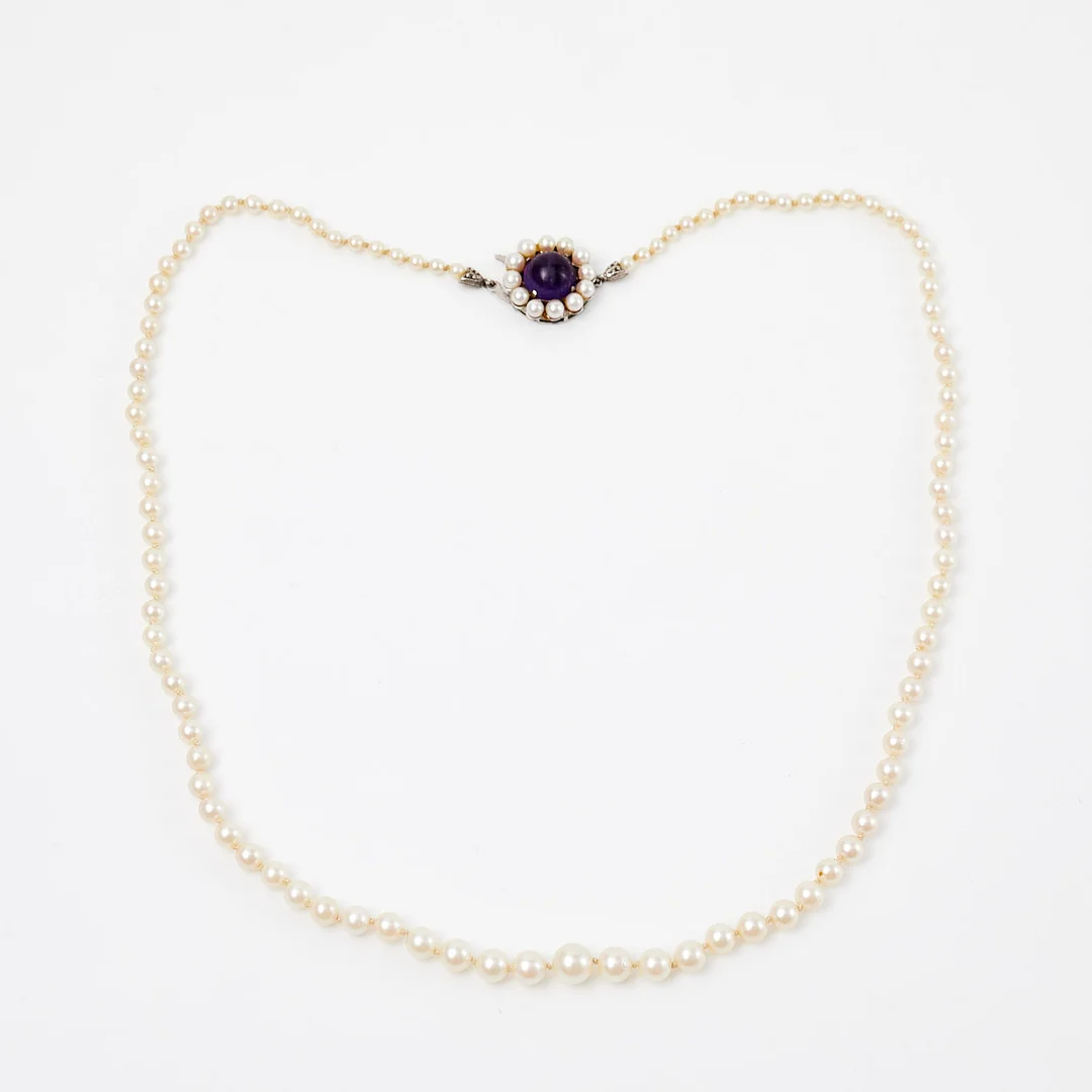 PÄRLHALSBAND, odlade saltvattenspärlor, ca 3-6 mm, lås i silver med dekor av ametist, J. Köhle, Pforzheim Tyskland, svenska importstämplar. — Necklace — Stockholms Auktionsverk Sickla