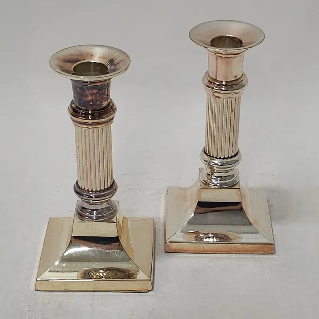 PAREJA DE CANDELEROS CON FORMA DE COLUMNA EN METAL PLATEADO.