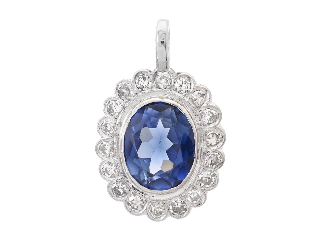 HÄNGE, platina, ovalslipad syntetisk blå safir, 18 gammal- och åttkantslipade diamanter ca 1,40 ctv, ca W-TCa/P, höjd på hänget 32 mm, vikt 7,9 g, safiren med små nagg, lagning vid öglan, några diamanter rmed nagg. — Smycken/Hänge — Kaplans