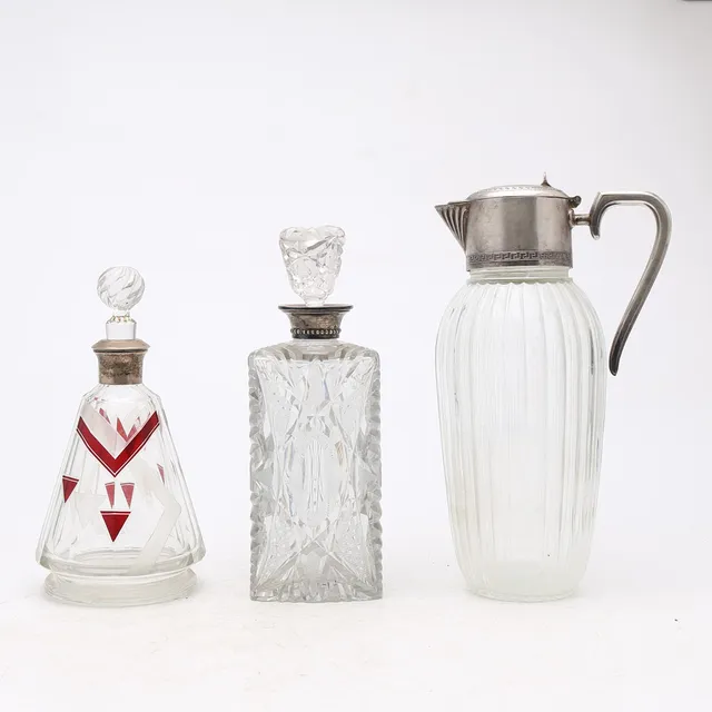 Two decanters in carved glass and silver and jug in glass and silvery metal, Art Deco and later, first half of the 20th Century.