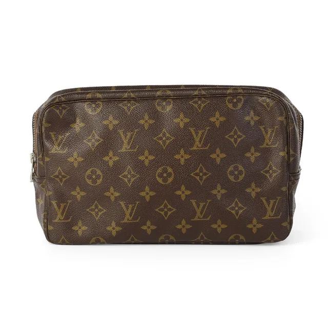 A “Trousse Toilette 28” of brown monogram canvas with silver tone hardware, one zipped compartment with an interior pocket, straps and beige lining. H. 18 x W. 28 x D. 8 cm.