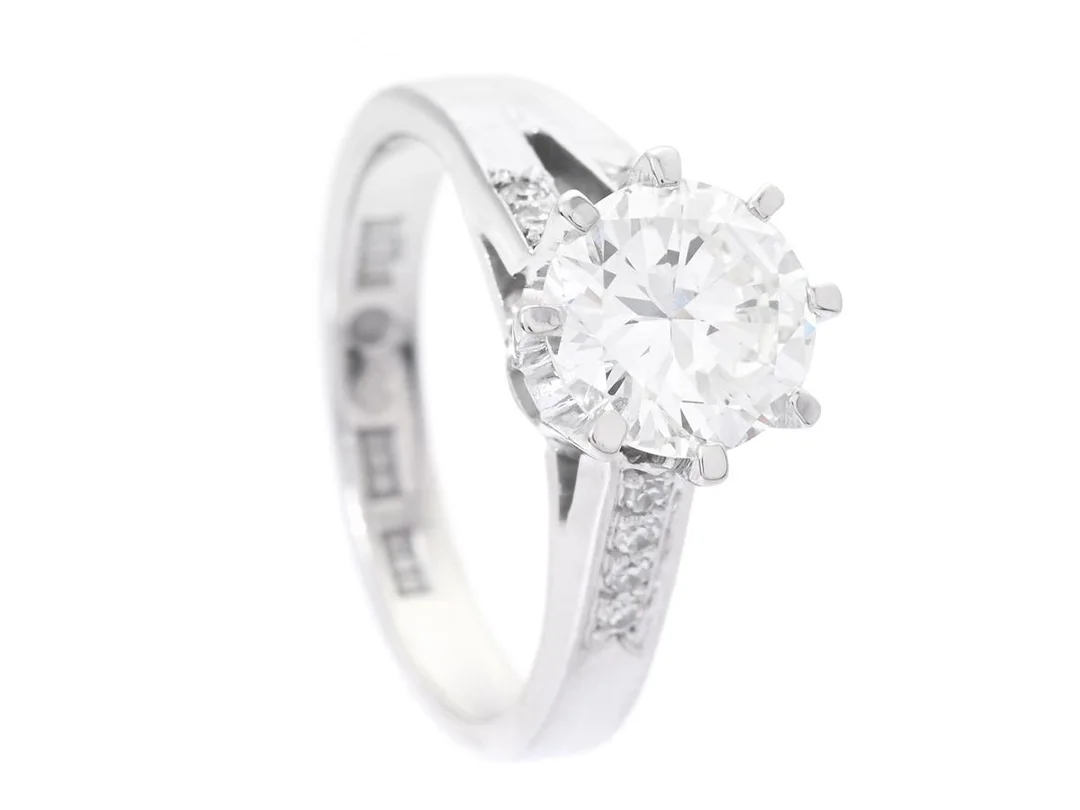 ENSTENSRING, 18K vitguld, briljantslipad diamant 1,54 ct enligt gravyr, ca W(H)/SI2, 8 åttkantslipade diamanter ca 0,08 ctv, Gabrielsons Guldsmedja, Stockholm 1979, stl 17 mm, vikt 6,2 g, den större diamanten har stort bord, låg krona, kulettfasett samt en skada invid rondisten. — Smycken/Enstensring — Kaplans
