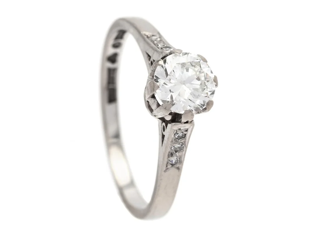 RING, 18K vitguld, briljantslipad diamant ca 0,60 ct, ca R(E)/VS2, 6 åttkantslipade diamanter ca 0,03 ctv, Guldsmedja Rosengren & Eriksson, Stockholm 1961, stl 16,75+ mm, vikt 2,6 g, fattningen är nedsliten, diamanten har liten kulettfasett. — Smycken/Ring — Kaplans